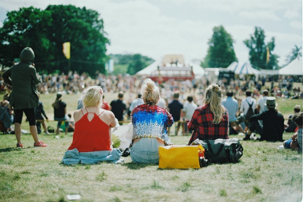 Girls sitting on lawn at an outdoor concert