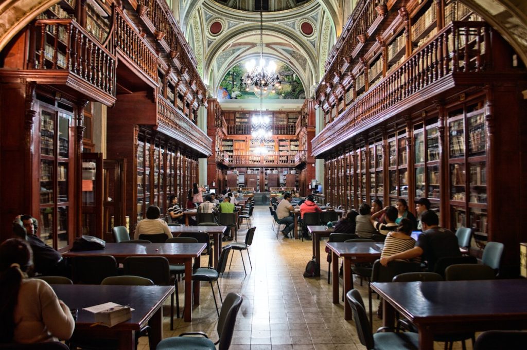 Library with books shelves on both sides and tables in the middle