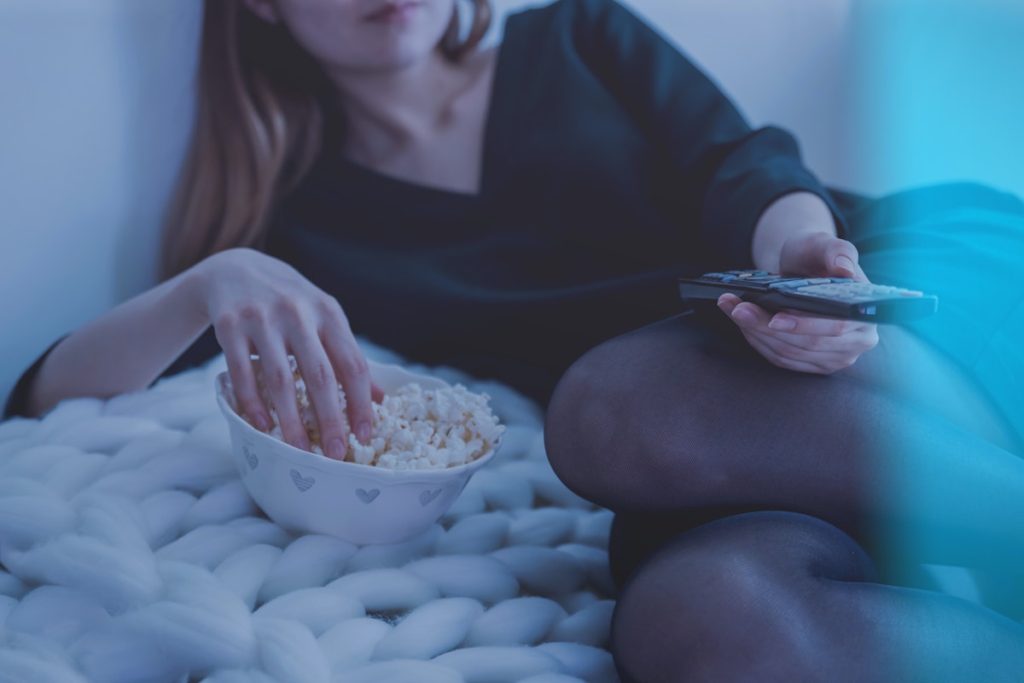 Lady with remote control and bowl of popcorn